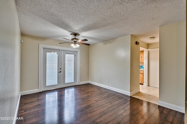 spare room with a textured ceiling, baseboards, wood finished floors, and french doors