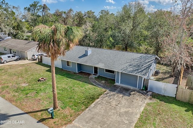 ranch-style house with a garage, fence, concrete driveway, roof with shingles, and a front lawn