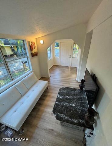 living room with arched walkways and wood finished floors