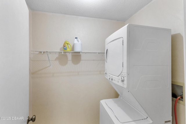 washroom with a textured ceiling, stacked washer and clothes dryer, and laundry area