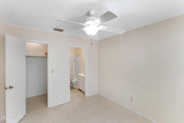 unfurnished bedroom featuring visible vents, a walk in closet, ensuite bathroom, a closet, and ceiling fan