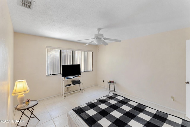 living area featuring visible vents, a ceiling fan, a textured ceiling, light tile patterned floors, and baseboards