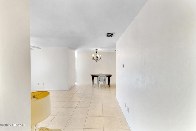 hallway featuring light tile patterned flooring, visible vents, and a chandelier