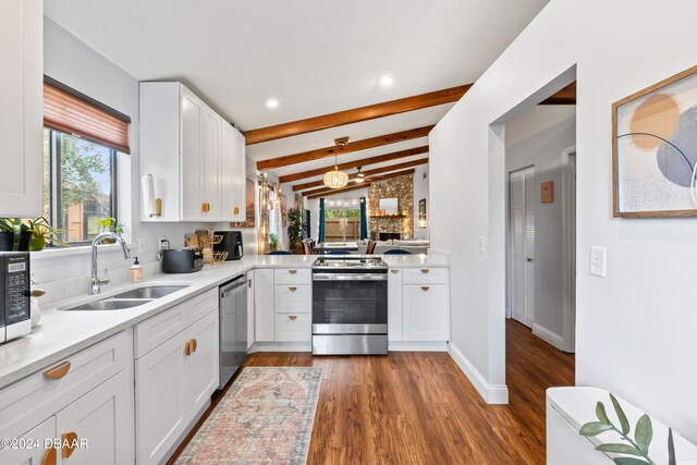 kitchen with stainless steel appliances, dark wood-type flooring, vaulted ceiling with beams, sink, and white cabinetry