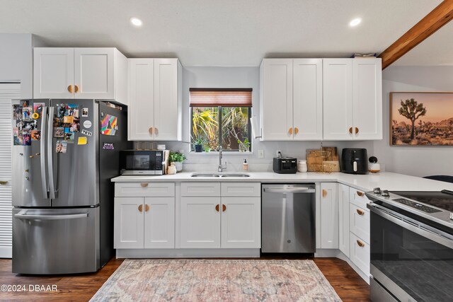 kitchen with stainless steel appliances, white cabinetry, sink, and dark wood-type flooring