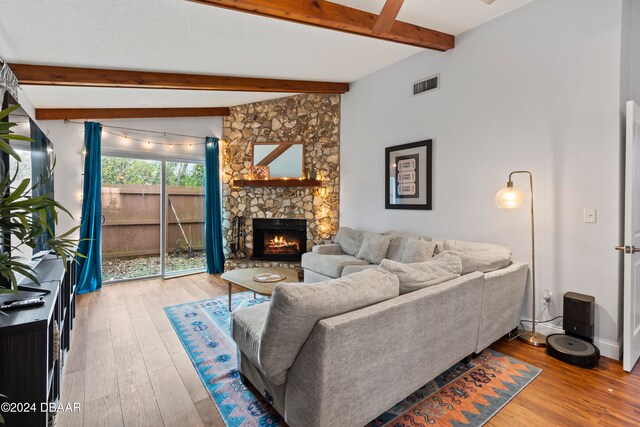 living room featuring lofted ceiling with beams, hardwood / wood-style floors, and a fireplace