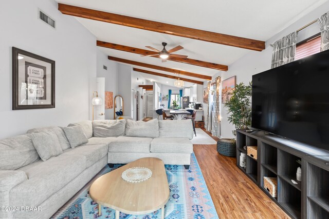 living room featuring wood-type flooring, vaulted ceiling with beams, and ceiling fan with notable chandelier