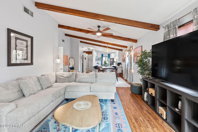 living room with lofted ceiling with beams, ceiling fan with notable chandelier, and wood-type flooring