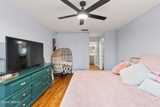 bedroom featuring hardwood / wood-style floors, ceiling fan, and connected bathroom