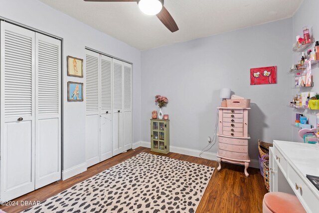 bedroom with ceiling fan, dark hardwood / wood-style floors, and multiple closets