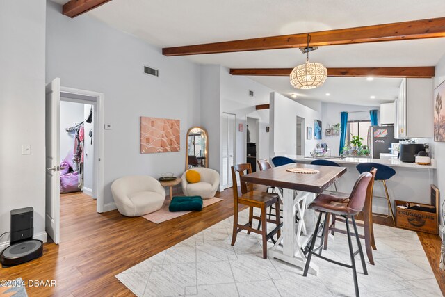 dining area with light hardwood / wood-style flooring and beamed ceiling