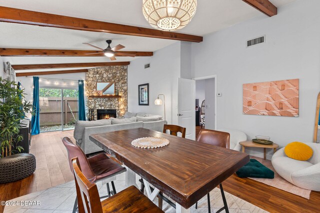 dining space with lofted ceiling with beams, light wood-type flooring, ceiling fan, and a fireplace