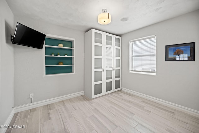 spare room featuring light hardwood / wood-style floors, a textured ceiling, and built in features