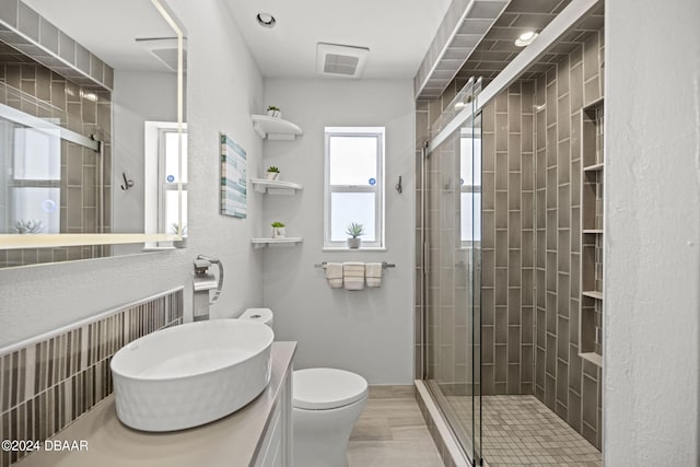 bathroom featuring toilet, vanity, and a shower with door