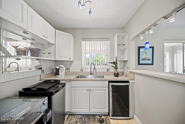 kitchen featuring wine cooler, pendant lighting, decorative backsplash, sink, and white cabinets