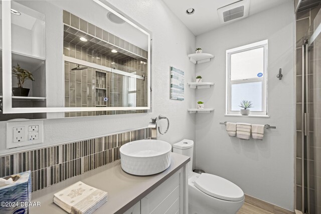 bathroom with wood-type flooring, vanity, toilet, and a shower with shower door