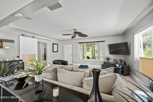 living room featuring plenty of natural light, a barn door, and ceiling fan