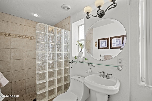 bathroom with toilet, sink, tiled shower, and a textured ceiling