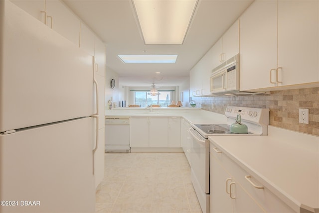 kitchen featuring white cabinets, decorative backsplash, a skylight, and white appliances