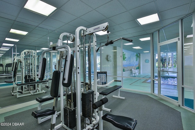 exercise room with a paneled ceiling and a healthy amount of sunlight