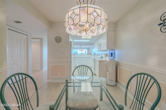4 Oceans W Blvd Unit 407B, Daytona Beach Shores, FL 32118 - dining area with a chandelier, light tile patterned floors, and wainscoting