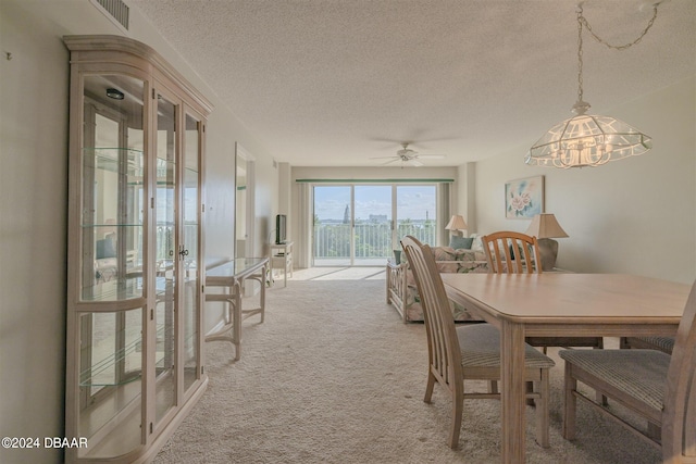 carpeted dining area featuring ceiling fan with notable chandelier and a textured ceiling