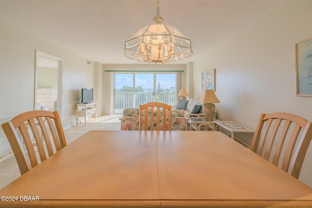 carpeted dining area featuring a textured ceiling and an inviting chandelier