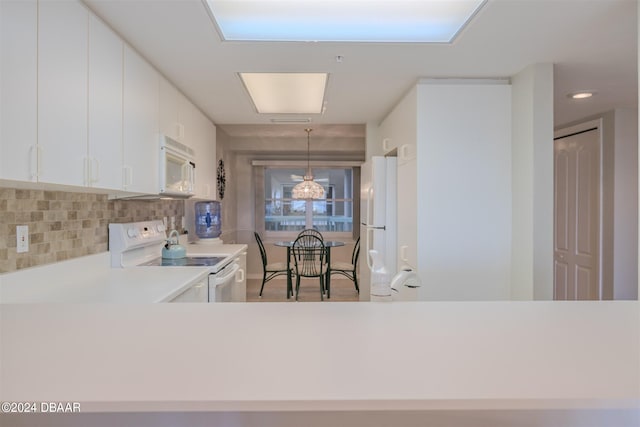 kitchen featuring white cabinetry, hanging light fixtures, white appliances, and backsplash