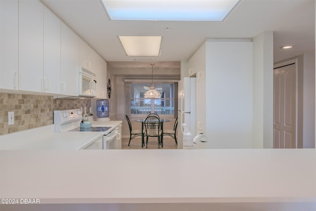 4 Oceans W Blvd Unit 407B, Daytona Beach Shores, FL 32118 - kitchen with white appliances, light countertops, decorative backsplash, white cabinetry, and pendant lighting