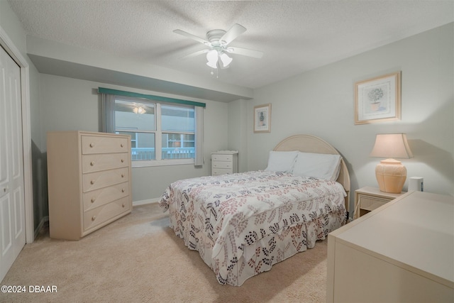 carpeted bedroom featuring a closet, a textured ceiling, and ceiling fan