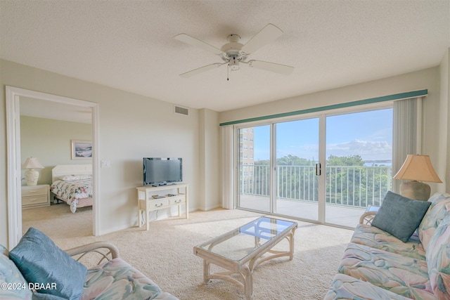 carpeted living room with a textured ceiling and ceiling fan