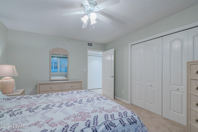 carpeted bedroom with a closet, a textured ceiling, and ceiling fan