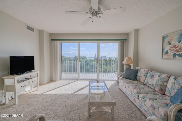 carpeted living room featuring a textured ceiling and ceiling fan