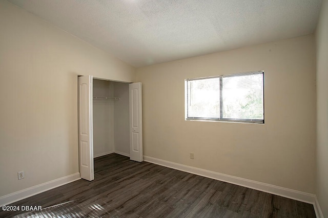 unfurnished bedroom with dark wood-type flooring, a textured ceiling, vaulted ceiling, and a closet