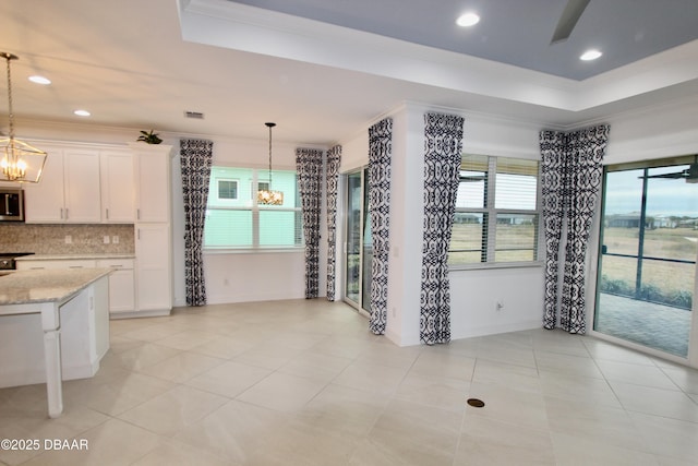 kitchen with a chandelier, white cabinets, hanging light fixtures, and light stone countertops