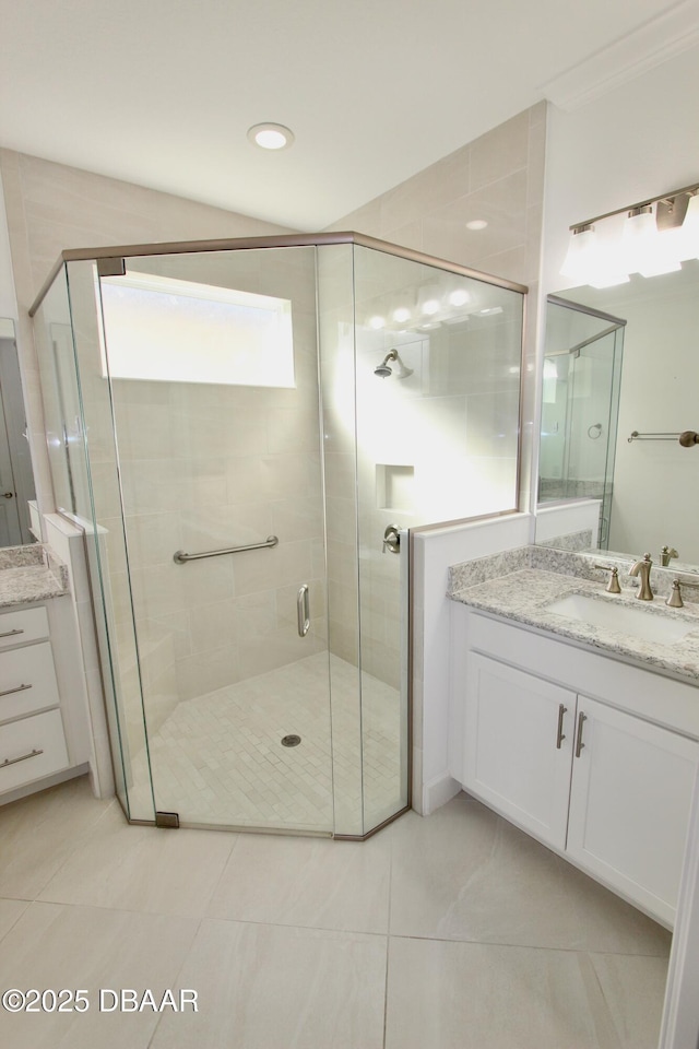 bathroom featuring a shower with door, tile patterned floors, and vanity