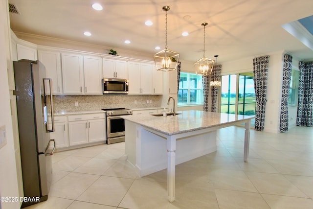 kitchen featuring white cabinets, appliances with stainless steel finishes, sink, hanging light fixtures, and a center island with sink