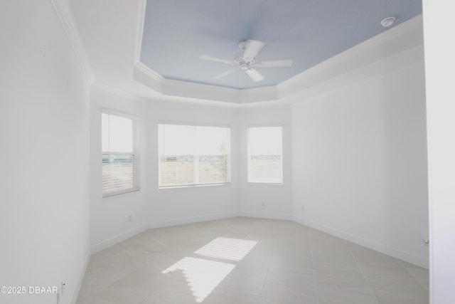 tiled spare room featuring ceiling fan, plenty of natural light, ornamental molding, and a raised ceiling