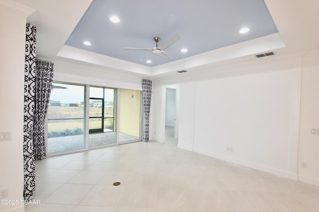 unfurnished room with a raised ceiling, ceiling fan, and crown molding