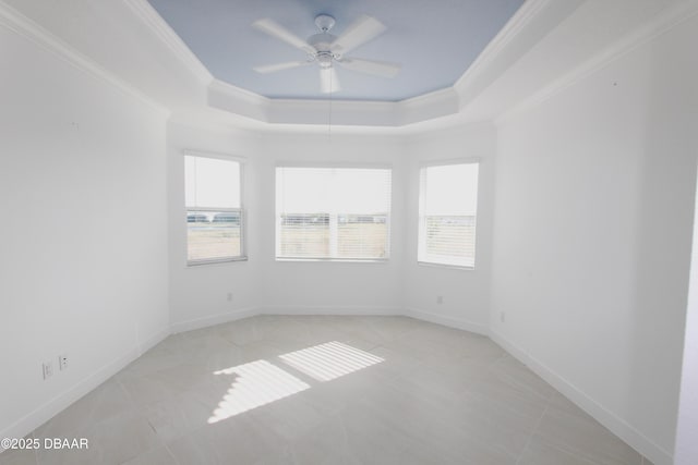 spare room with ceiling fan, a tray ceiling, and crown molding