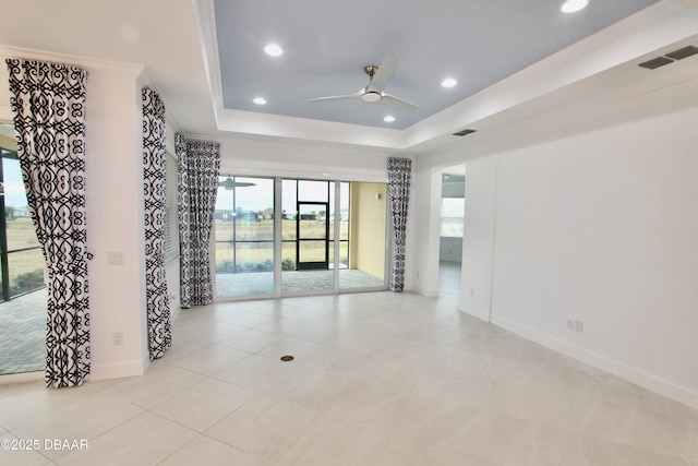 spare room with a raised ceiling, light tile patterned floors, and ceiling fan