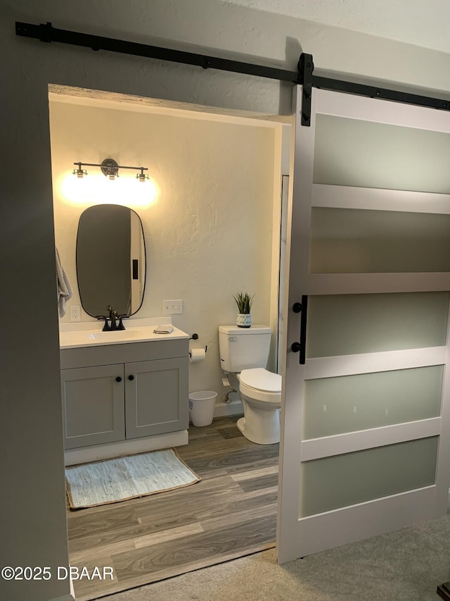 bathroom with vanity, toilet, and wood-type flooring