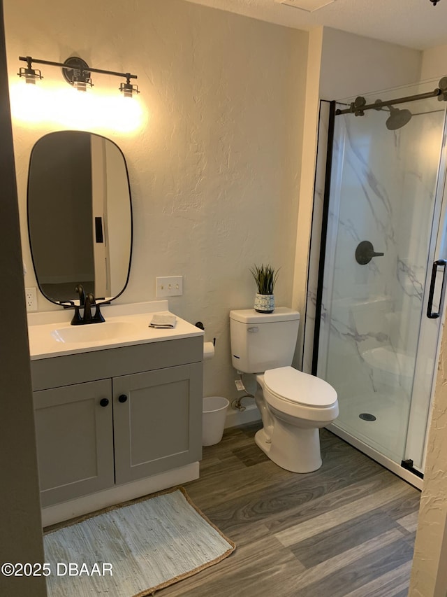 bathroom featuring walk in shower, wood-type flooring, toilet, and vanity