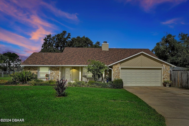 ranch-style home featuring a garage, a porch, and a lawn