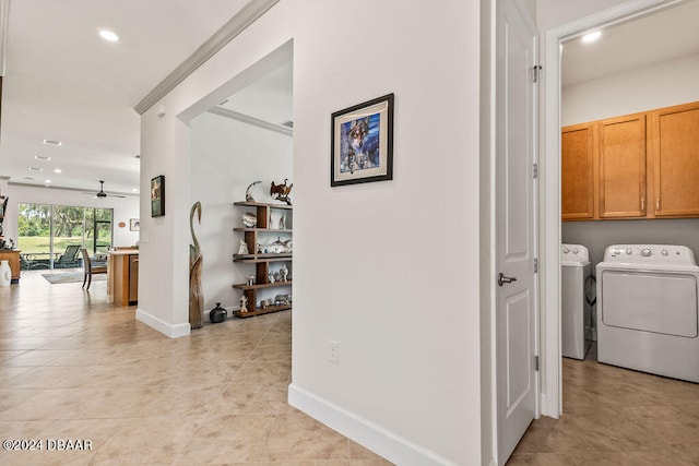 hallway featuring washer and clothes dryer, light tile patterned floors, and ornamental molding