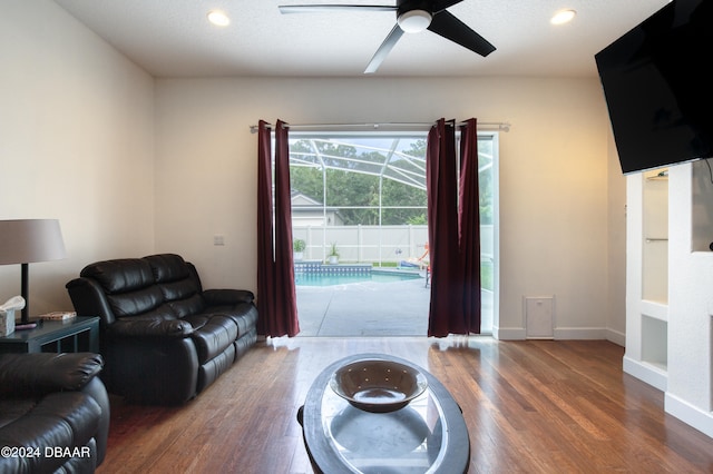 living room with dark wood-type flooring, a textured ceiling, and ceiling fan