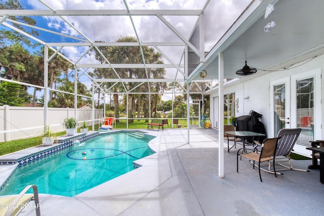 view of swimming pool featuring glass enclosure, ceiling fan, and a patio area