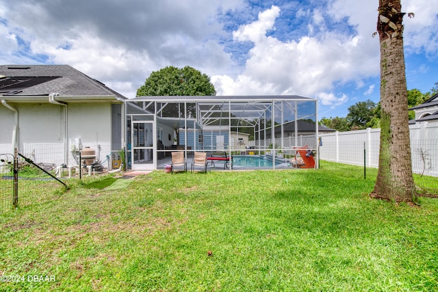 back of property with a fenced in pool, glass enclosure, a patio area, and a yard