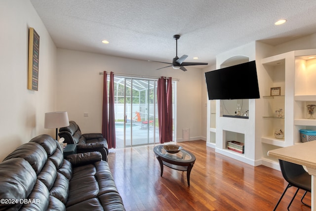 living room with hardwood / wood-style flooring, ceiling fan, a textured ceiling, and built in shelves