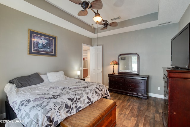 bedroom featuring dark wood-type flooring, ceiling fan, and a raised ceiling